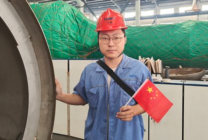 工人在绿网包裹的塔器筒体旁