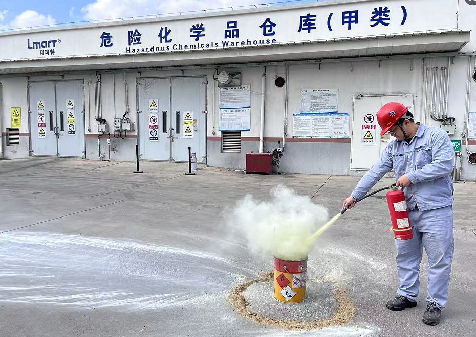 危险化学品仓库前,员工使用干粉灭火器扑灭模拟起火的油漆桶